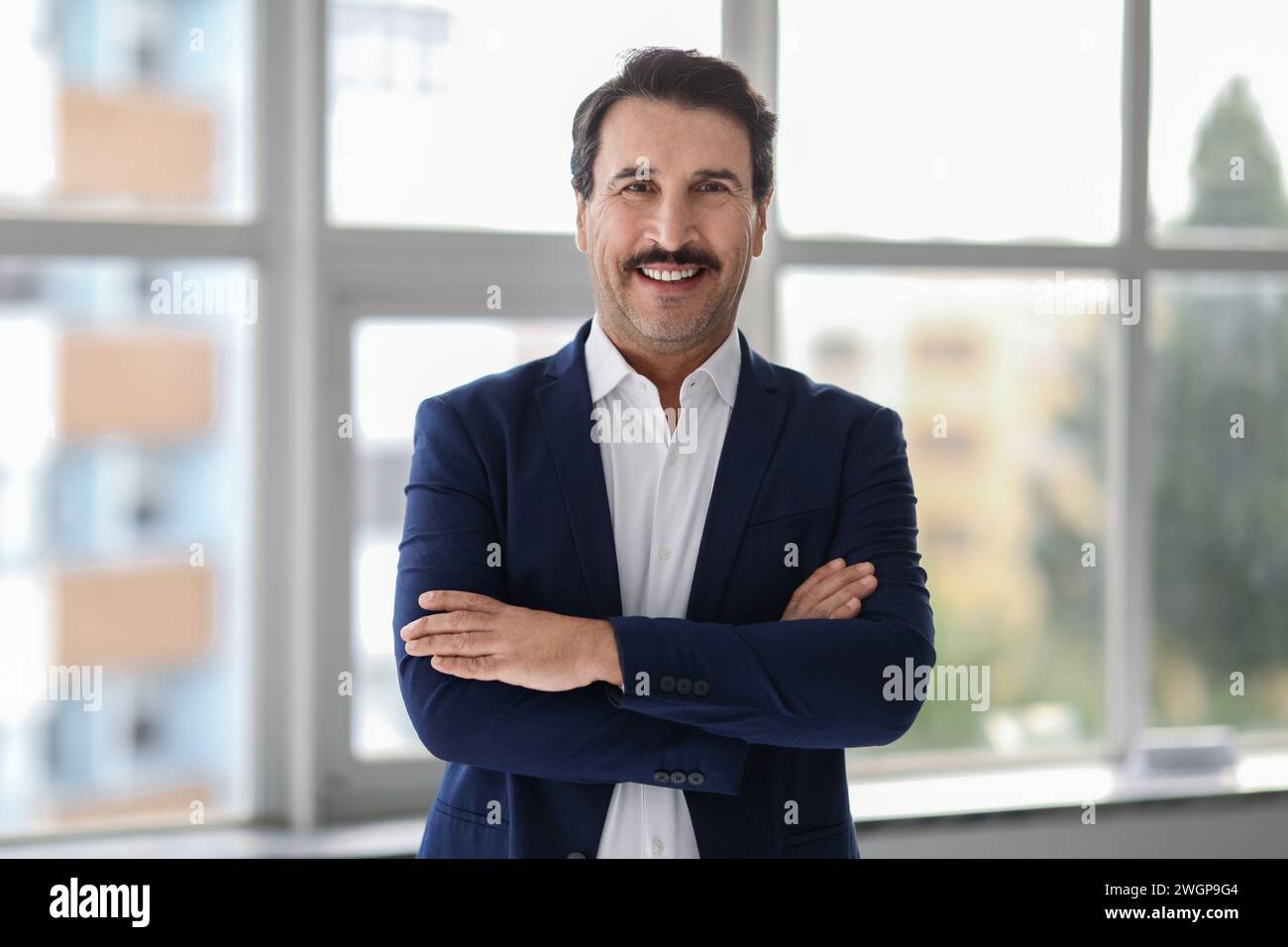 Confident middle-aged man with a mustache, wearing a blue suit and white shirt Stock Photo