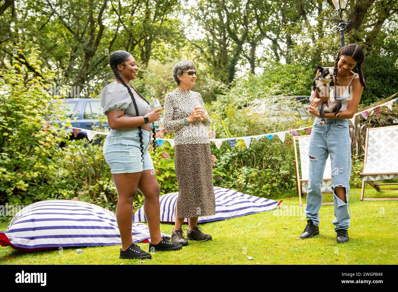 Mixed group of female friends and family gathering to have fun and  enjoy a summer BBQ garden party . Stock Photo