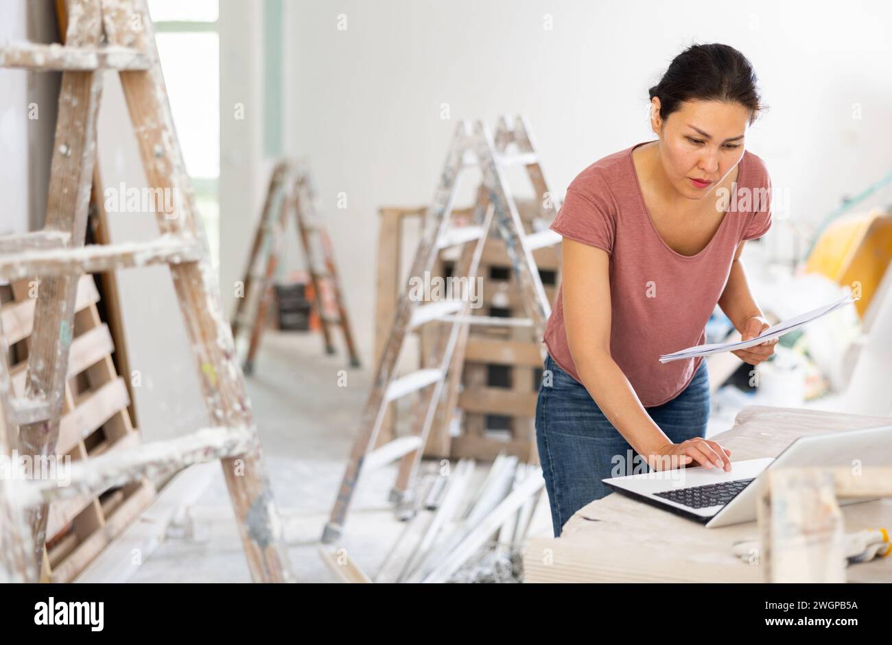 Woman construction manager checking project documentation, using laptop Stock Photo