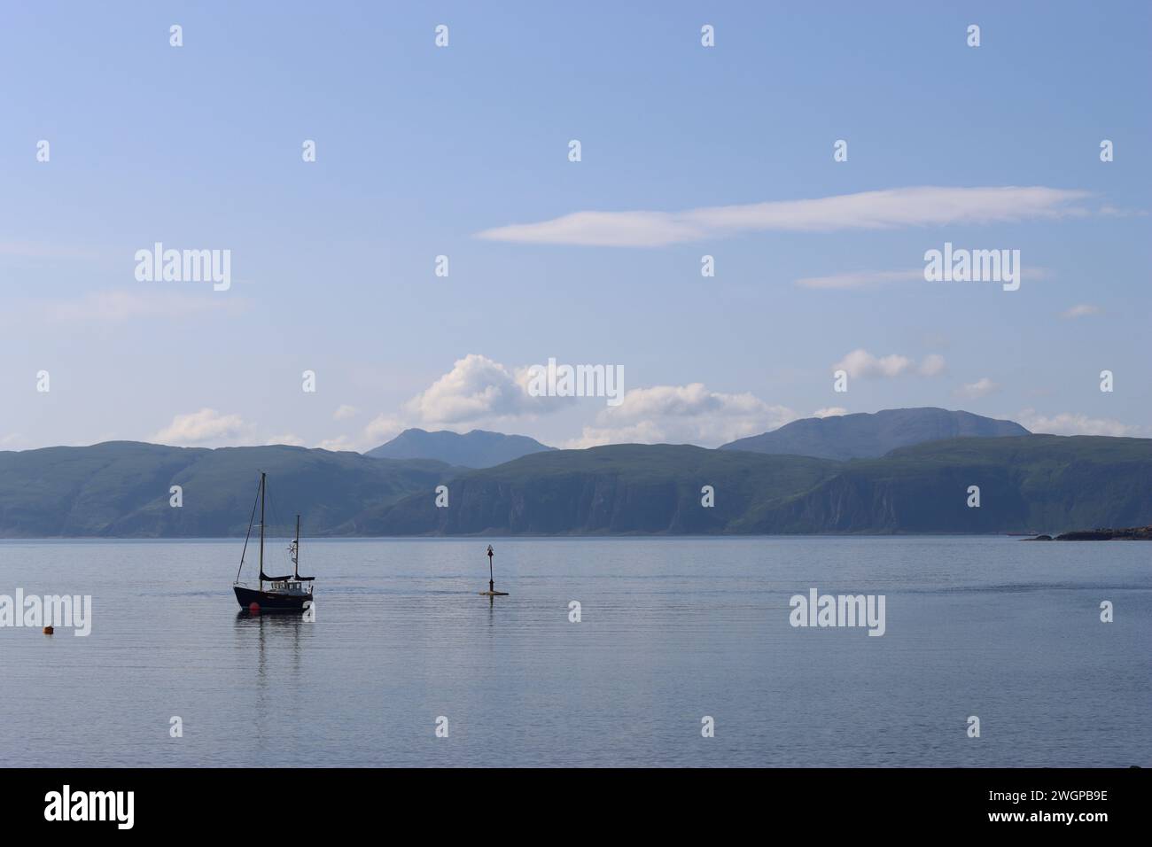 Boats on a calm smooth sea loch, with islands in the background Stock Photo