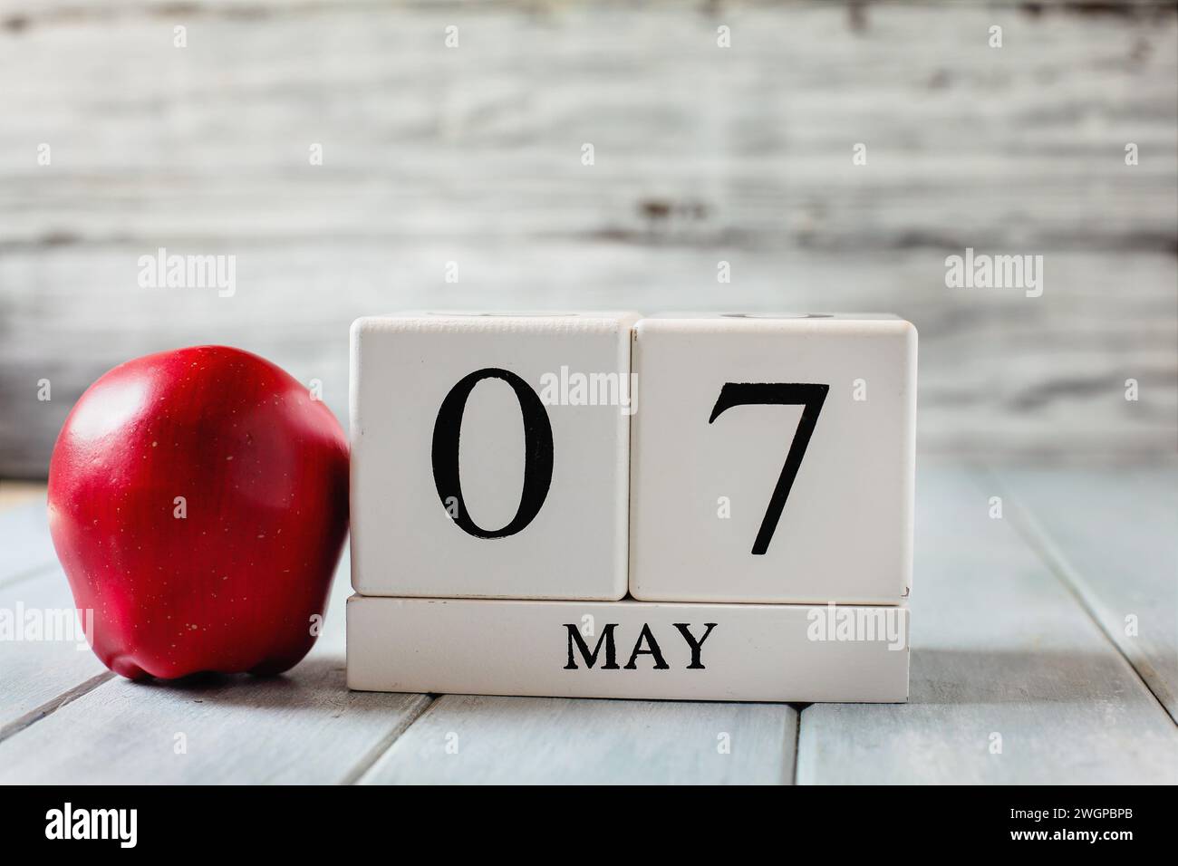 White wood calendar blocks with the date May 7th and a red apple for National Teacher Appreciation Day. Stock Photo