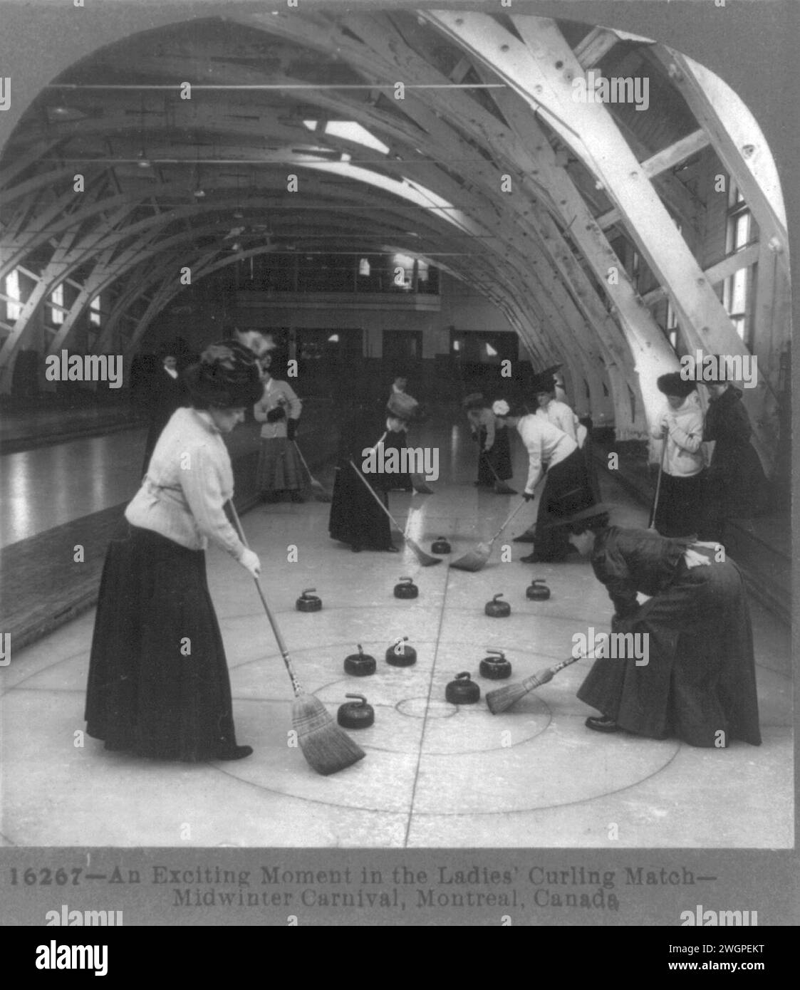 Vintage Photography showing activity of the annual  Midwinter carnival in Montreal.  Here in the ladies' curling match. Depicts ladies all dressed up with hats playing curling on an inside facility.  Circa 1900 Stock Photo