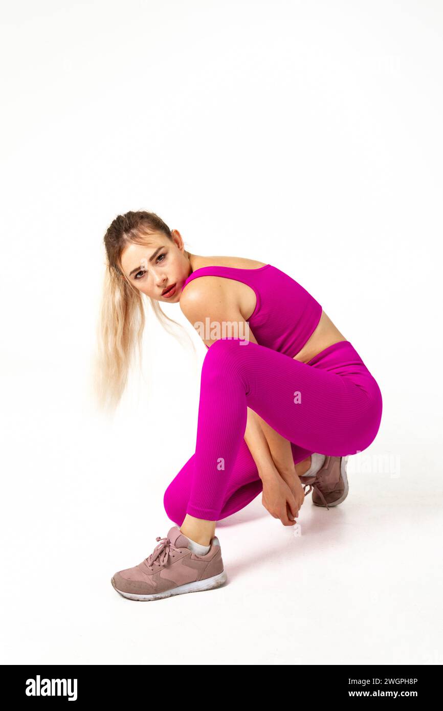 Woman in vibrant pink sports outfit with one knee on floor and other ...