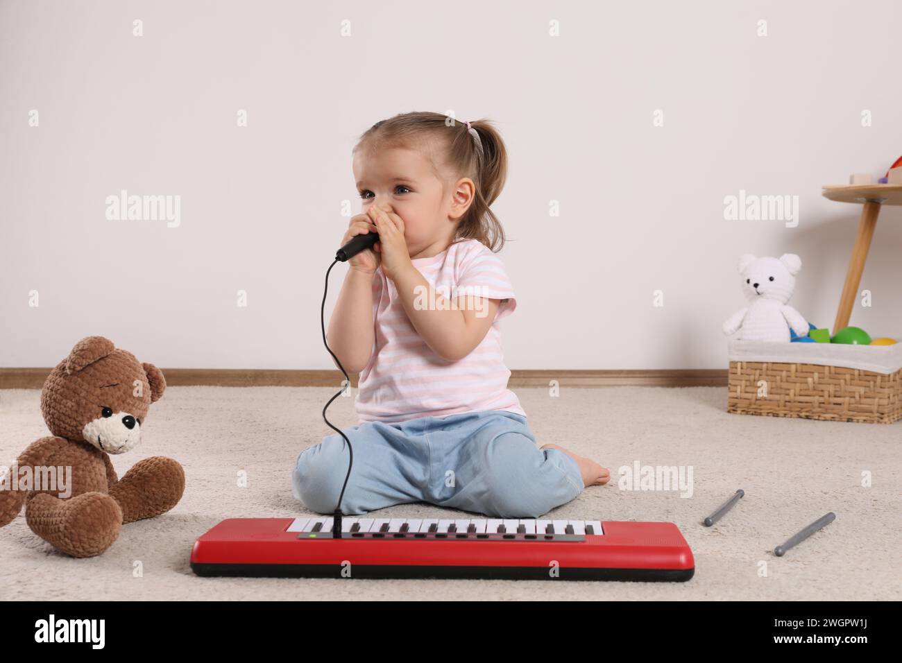 Cute little girl singing with toy piano and microphone at home Stock Photo