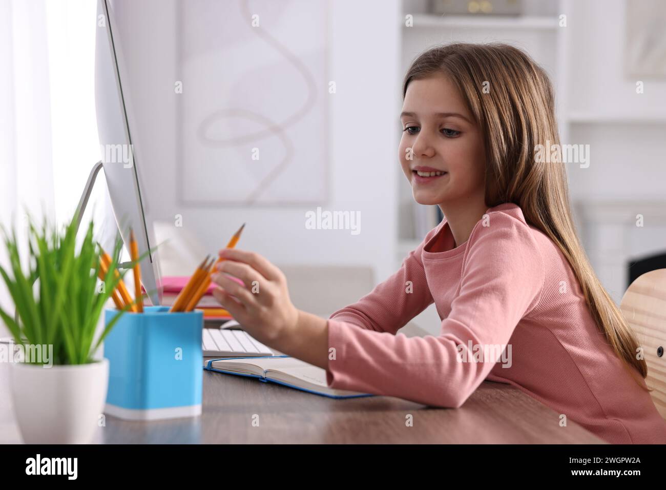 E-learning. Cute girl using computer during online lesson at table ...