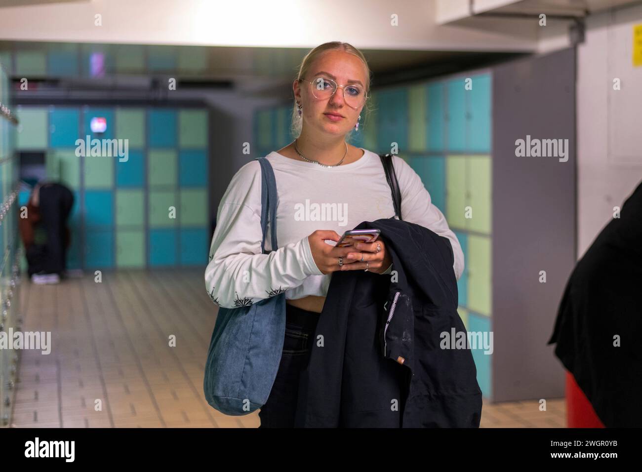 Teenage student on her phone at university Stock Photo