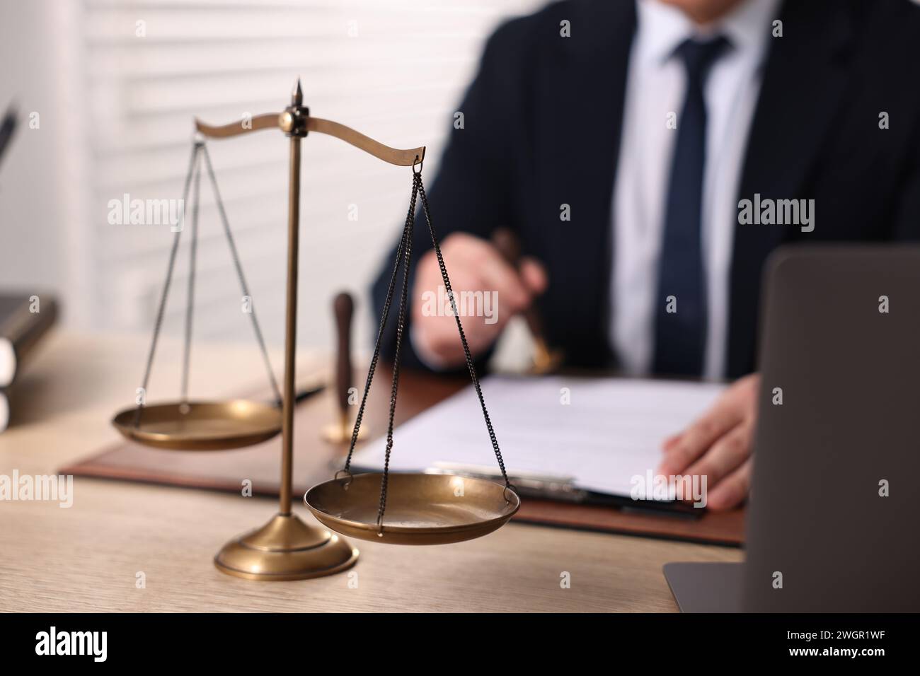 Notary stamping document at wooden table in office, focus on scales of ...