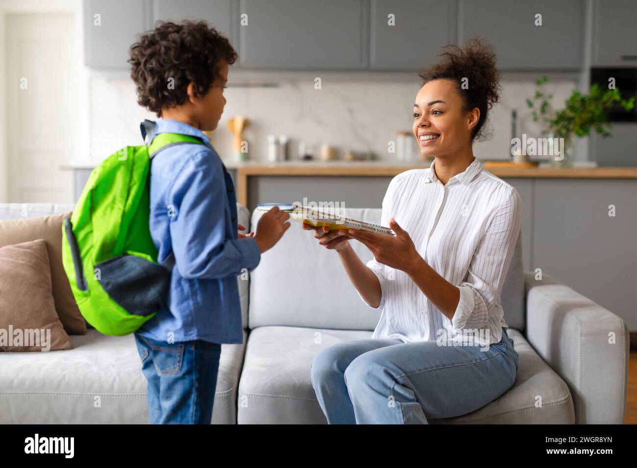 Black mother gives son copybooks, preparing for school Stock Photo - Alamy