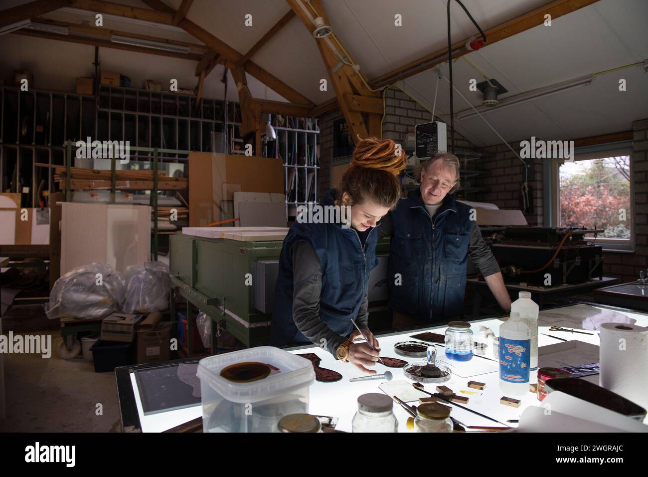 Apprentice female stained glass worker being taught lessons from