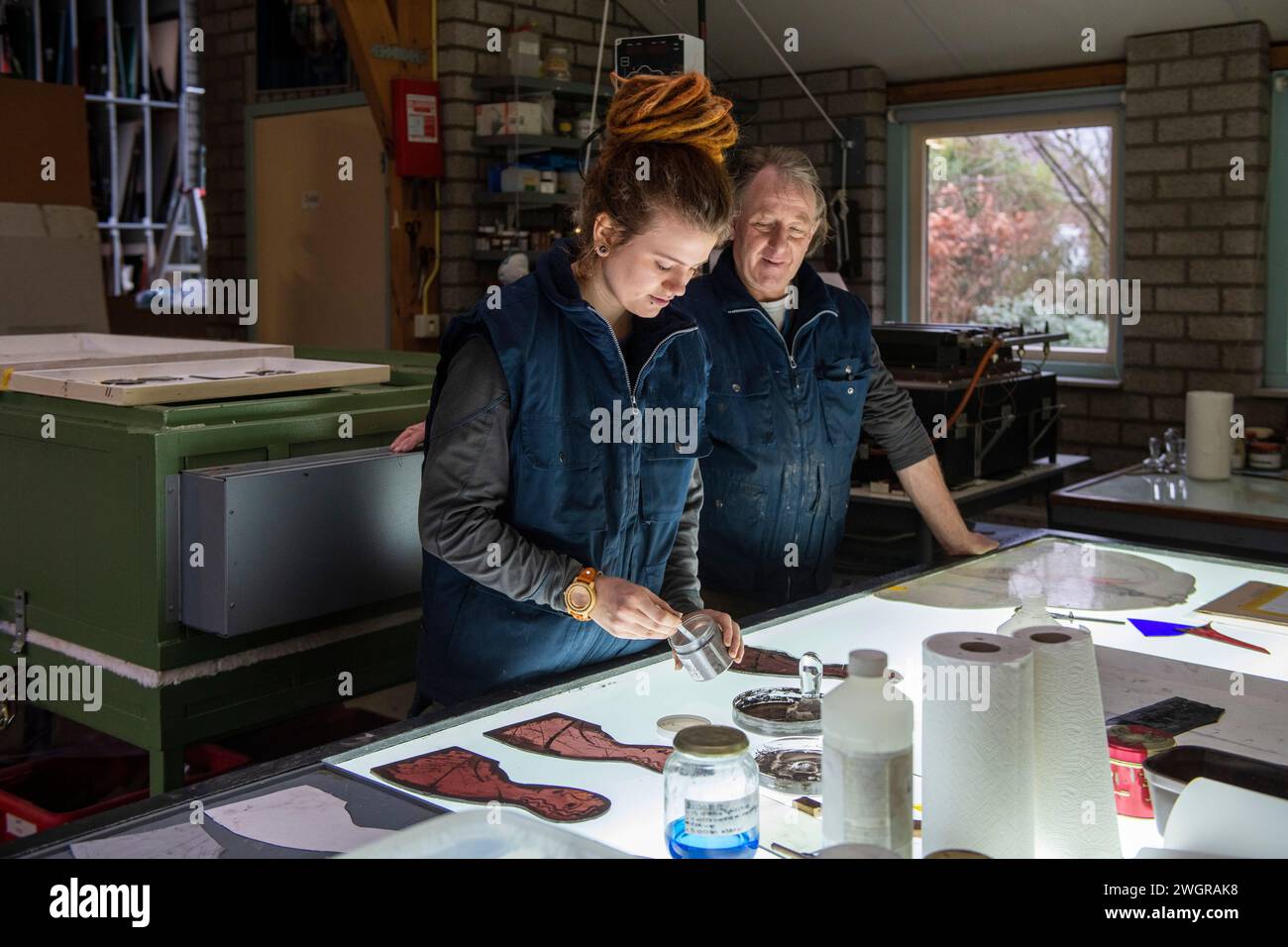Apprentice female stained glass worker being taught lessons from