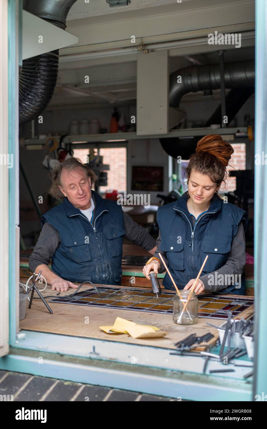 Apprentice female stained glass worker being taught lessons from