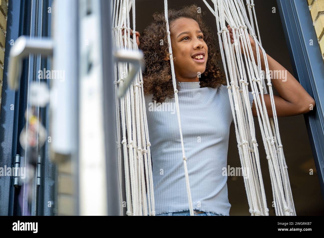 Mixed race teenage girl with amazing big curly hair looking out the back door Stock Photo