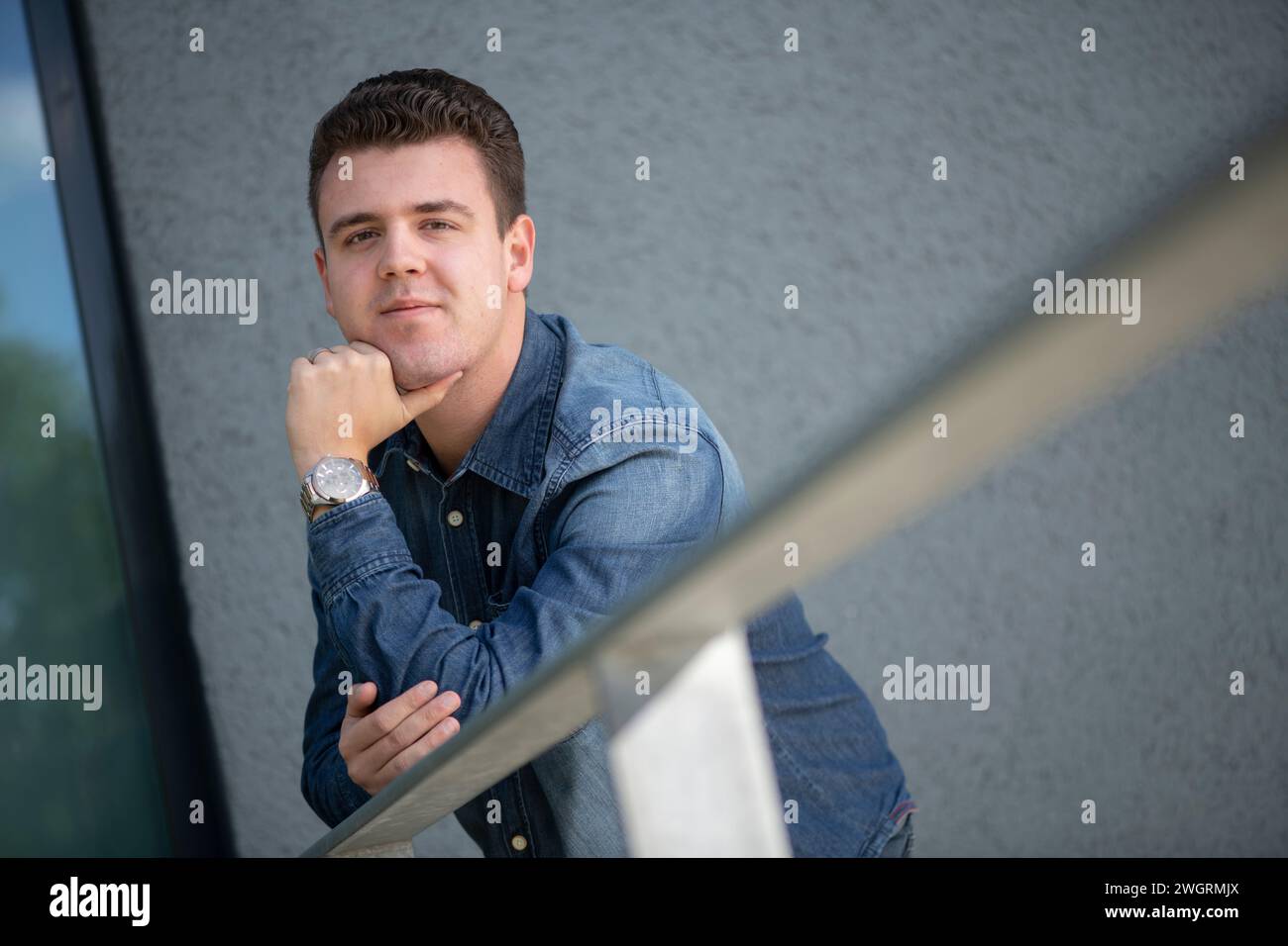 White young attractive male portrait against a grey textured wall. leaning and relaxing Stock Photo