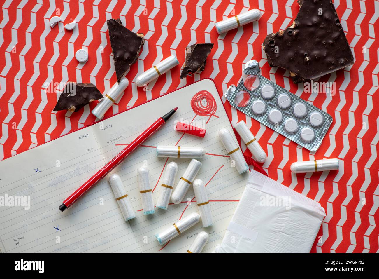 Female hygiene products lay out on a bed. Paracetamol, Sanitary pad, tampon, Chocolate Stock