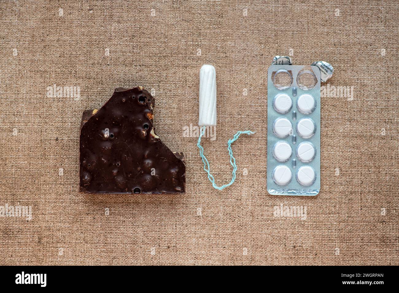 Female hygiene products lay out on a bed. Paracetamol, Sanitary pad, tampon, Chocolate Stock