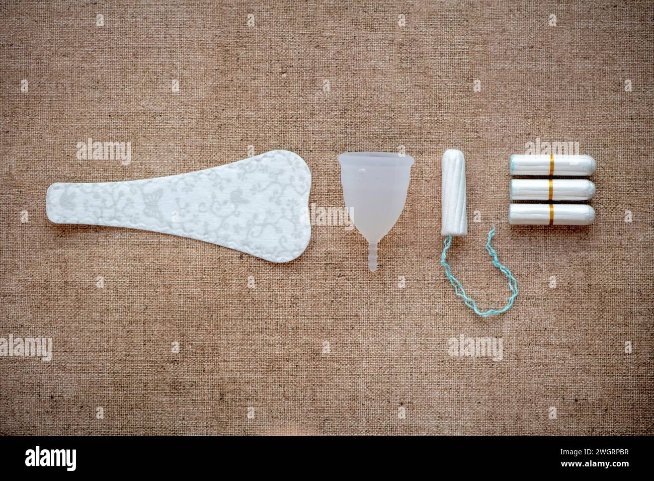 Female hygiene products lay out on a bed. Paracetamol, Sanitary pad, tampon, Chocolate Stock