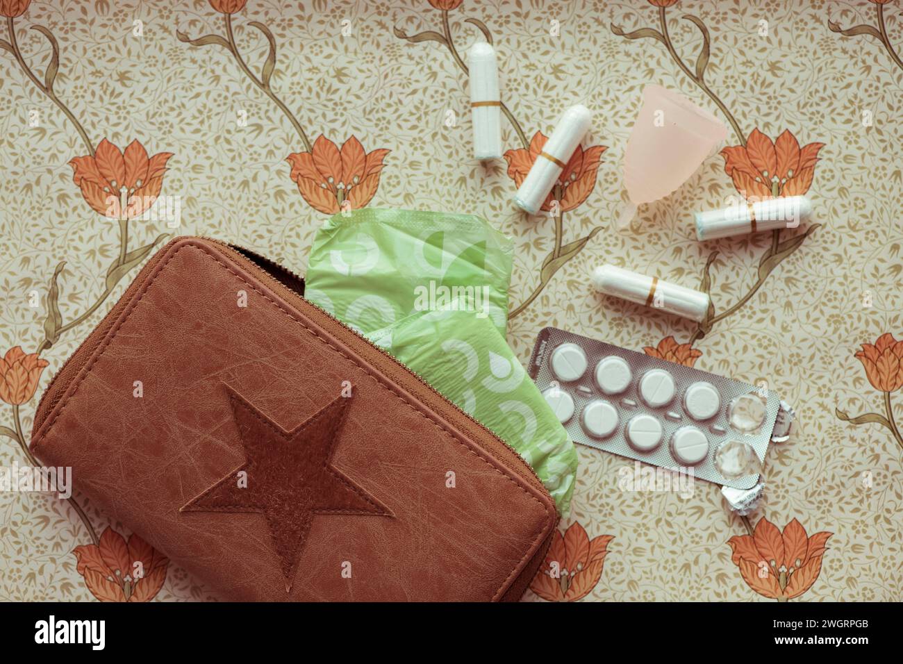 Female hygiene products lay out on a bed. Paracetamol, Sanitary pad, tampon, Chocolate Stock