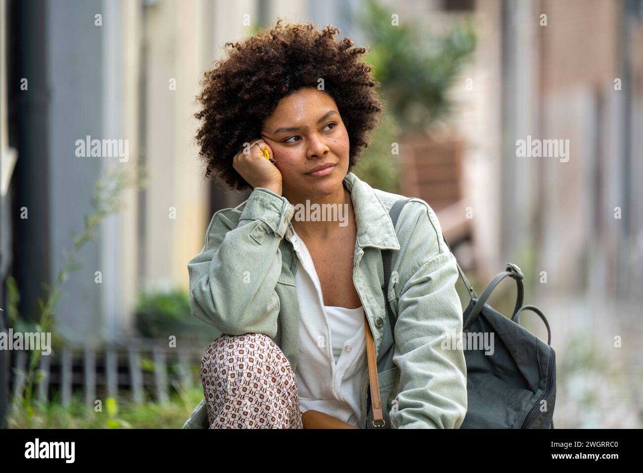 Young trendy woman sitting outside her apartment thinking and relaxing with the day Stock Photo