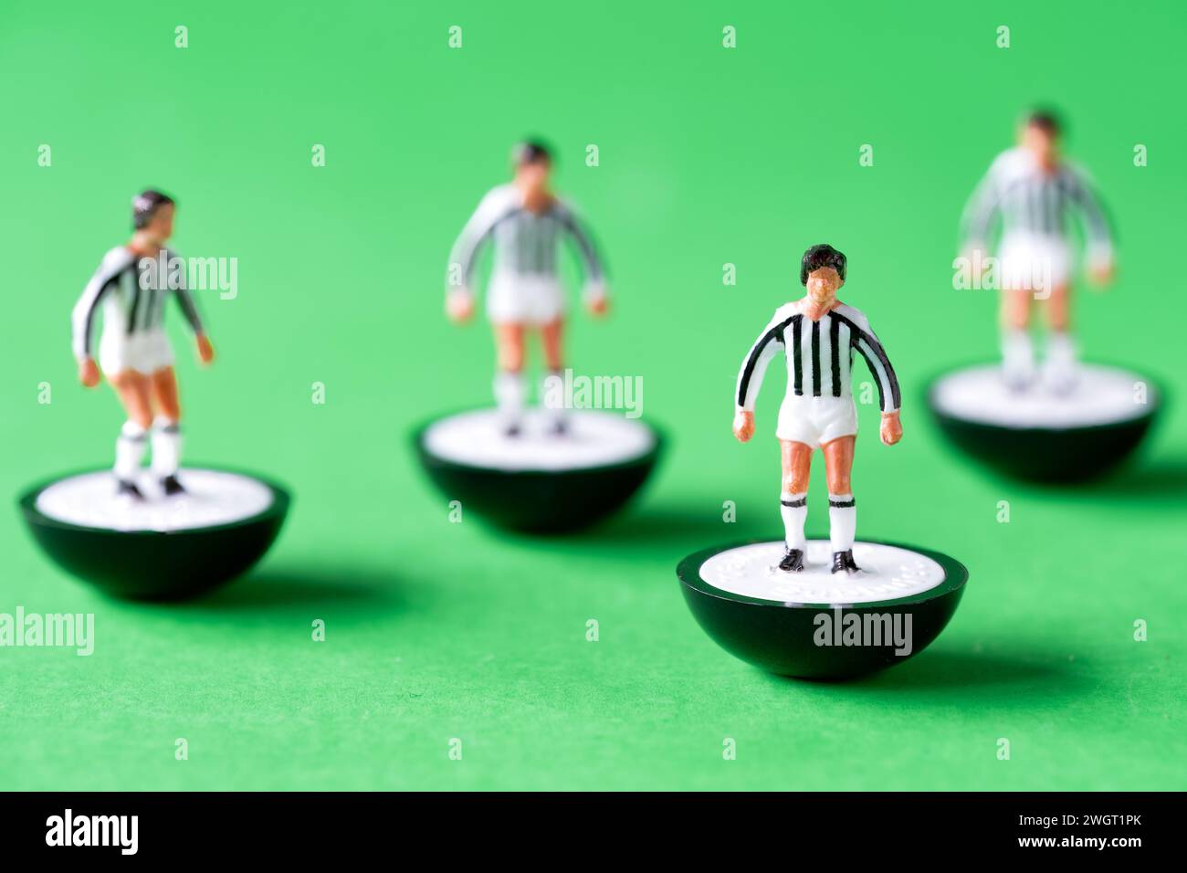 A group of Subbuteo miniature figures painted in the Juventus team colours of white and black striped shirts and white shorts. Stock Photo