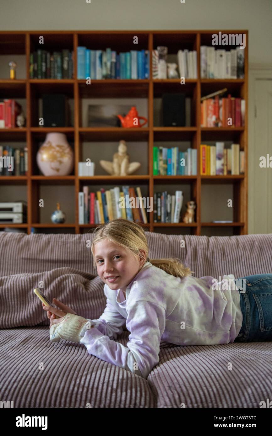 Young teenager relaxing on the sofa researching using her phone Stock Photo