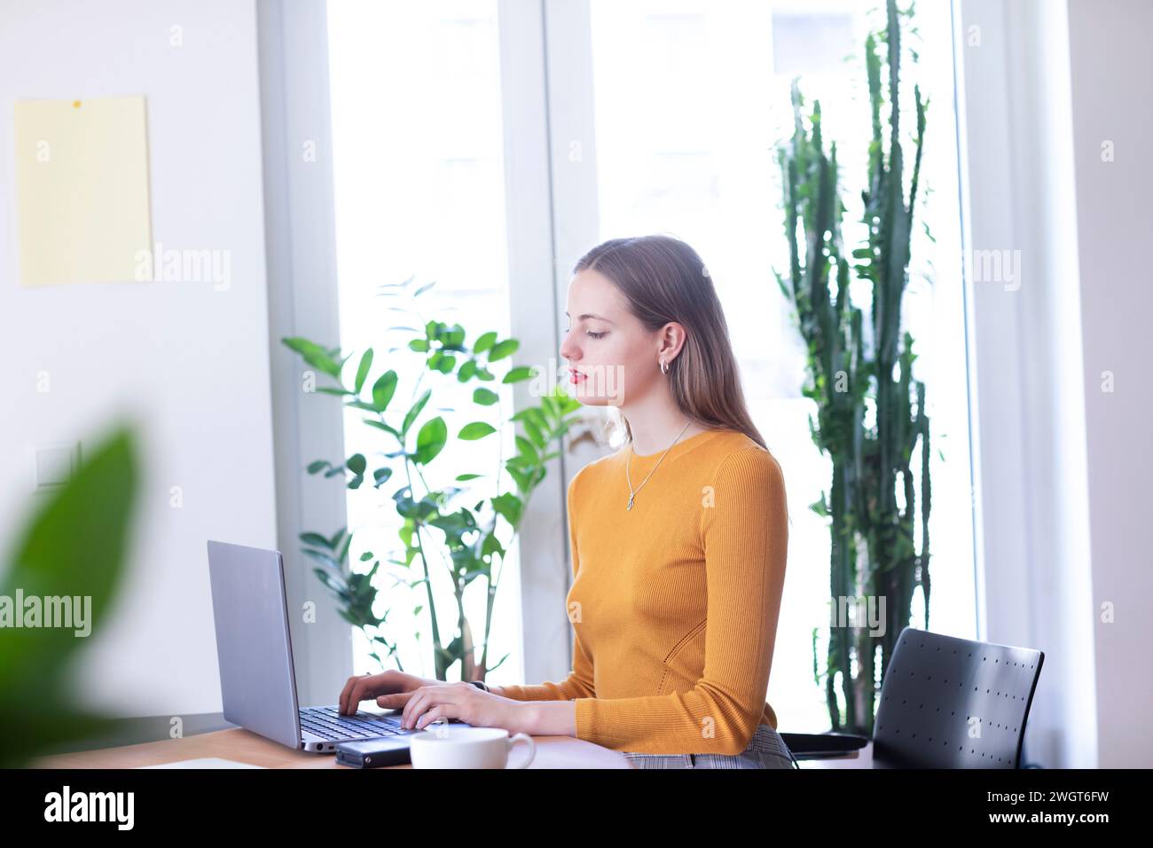 young woman in a room with green plants, home office Stock Photo