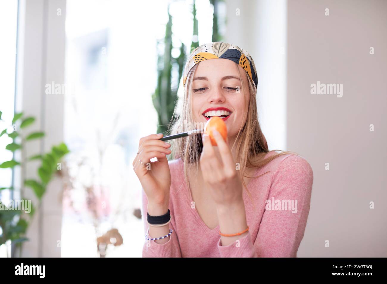 young woman with blond hair practices make-up with an egg Stock Photo