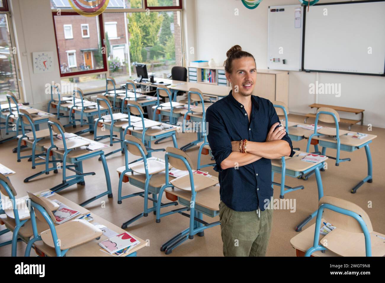 Primary school teacher standing in his empty classroom waiting for the children to arrive Stock Photo