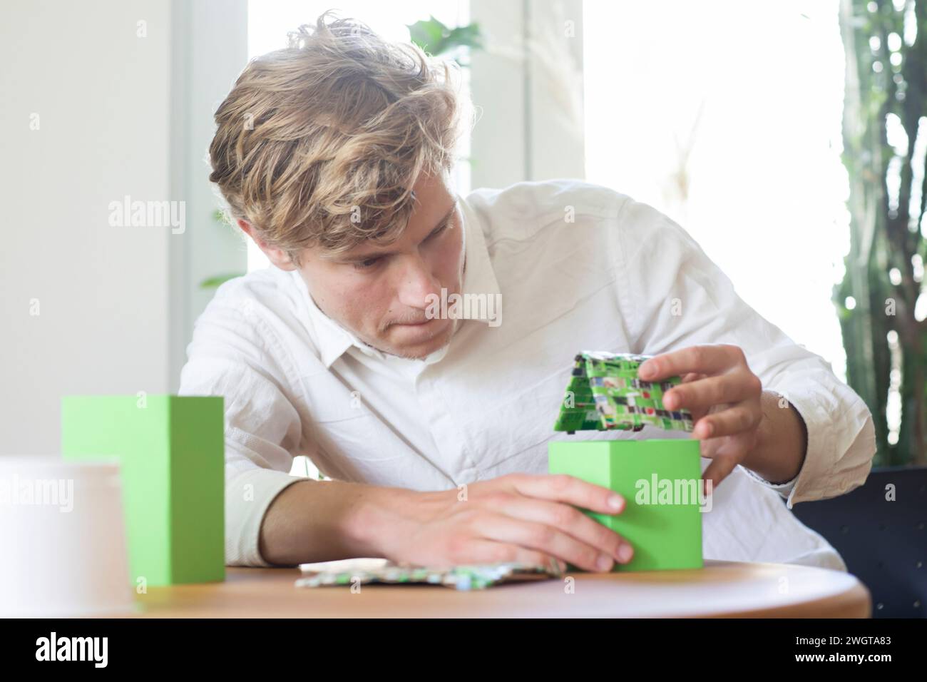Young man building a green energy house model Stock Photo