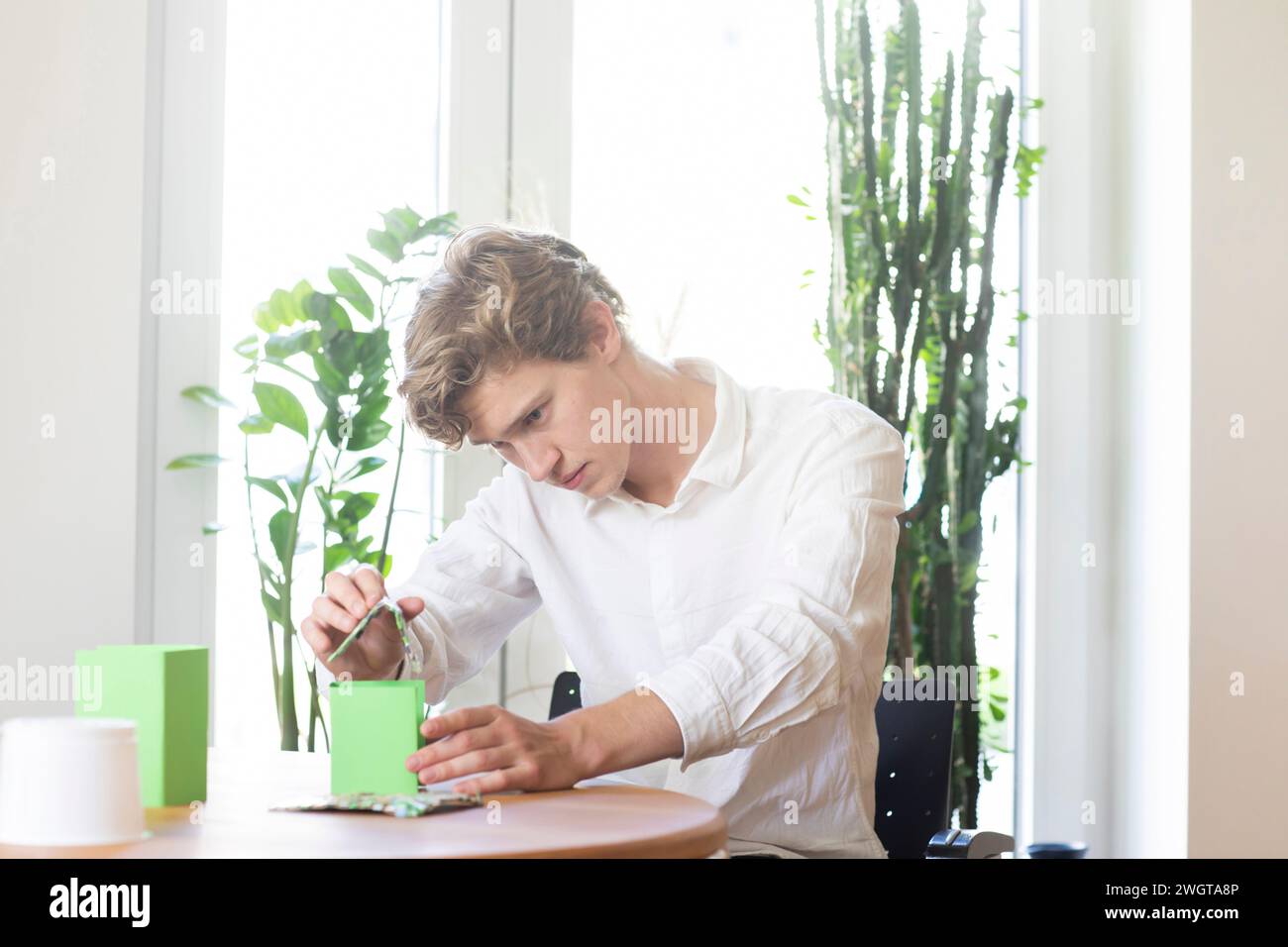 Young man building a green energy house model Stock Photo