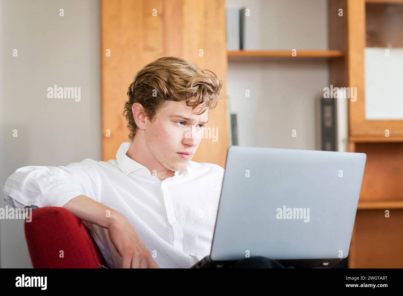 Young man sitting with laptop at home Stock Photo