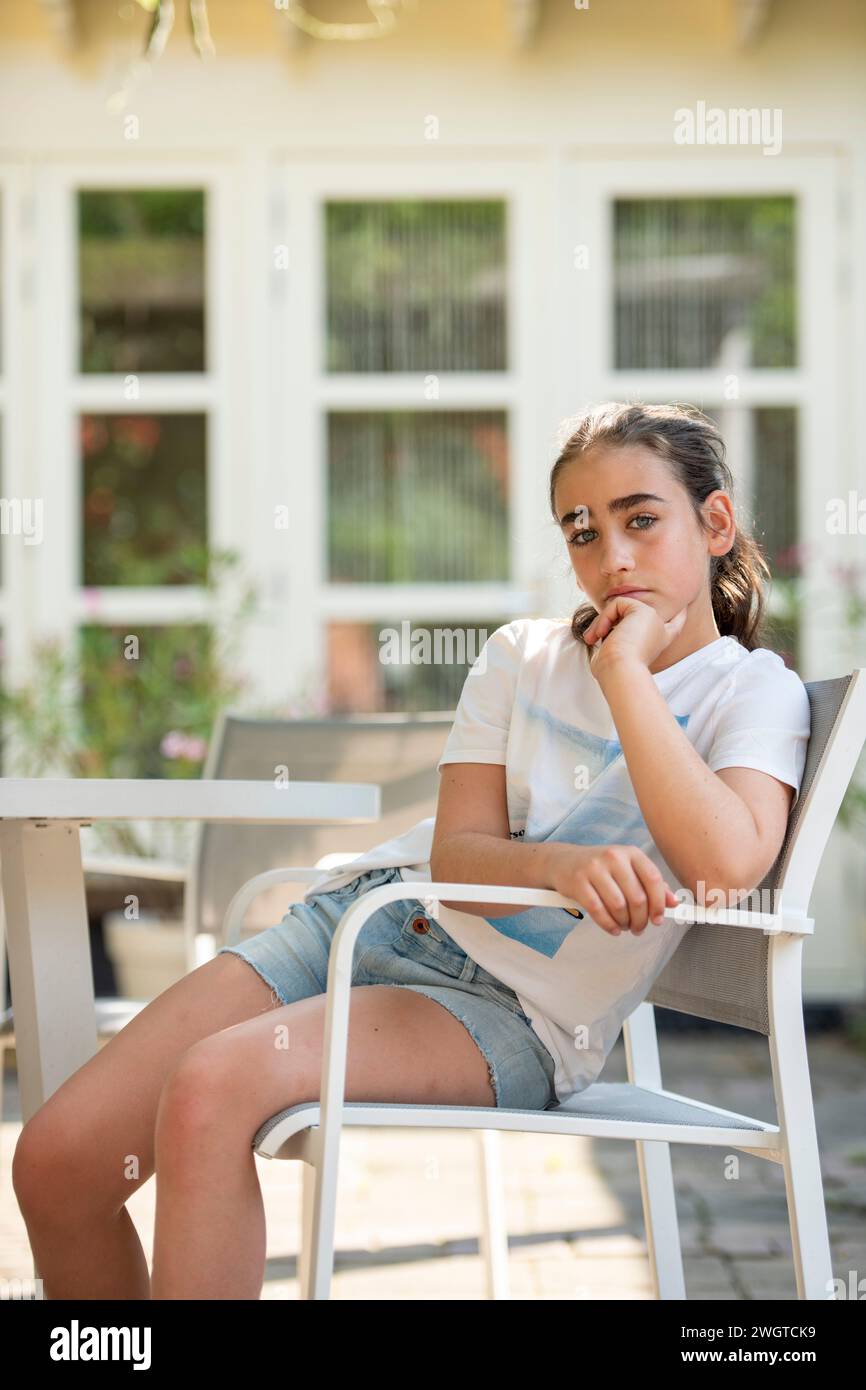Young girl sitting on a chair in her garden upset Stock Photo