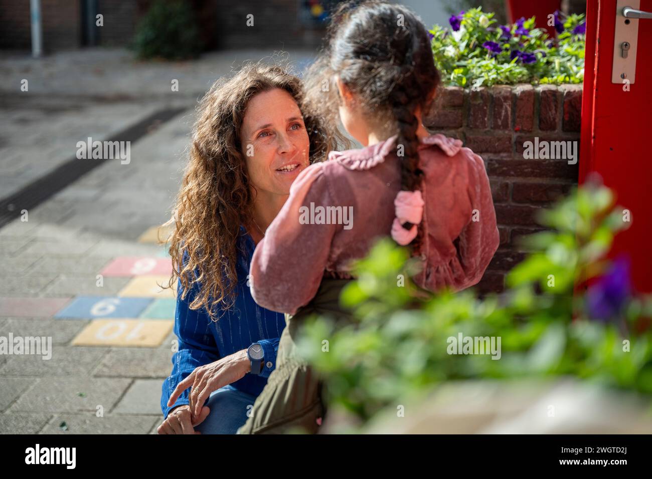 Teacher speaking to a young girl who is upset in the playground Stock Photo