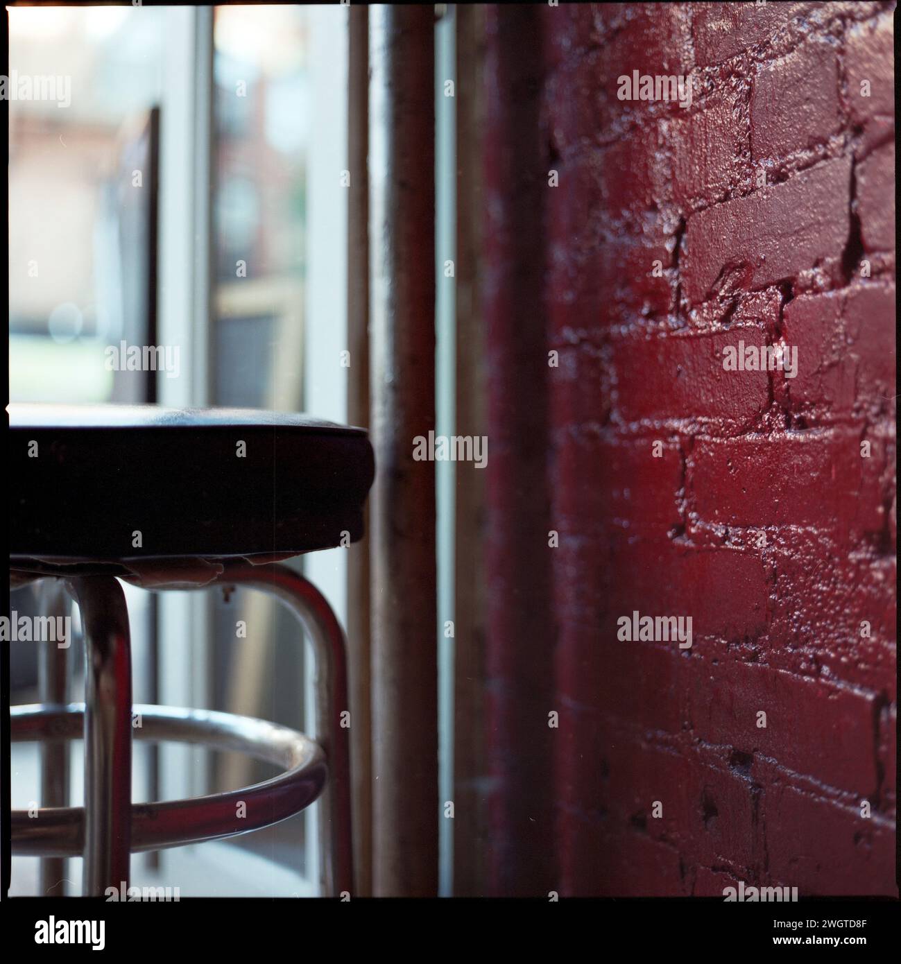 A bar stool near a red brick wall, New York City, USA Stock Photo