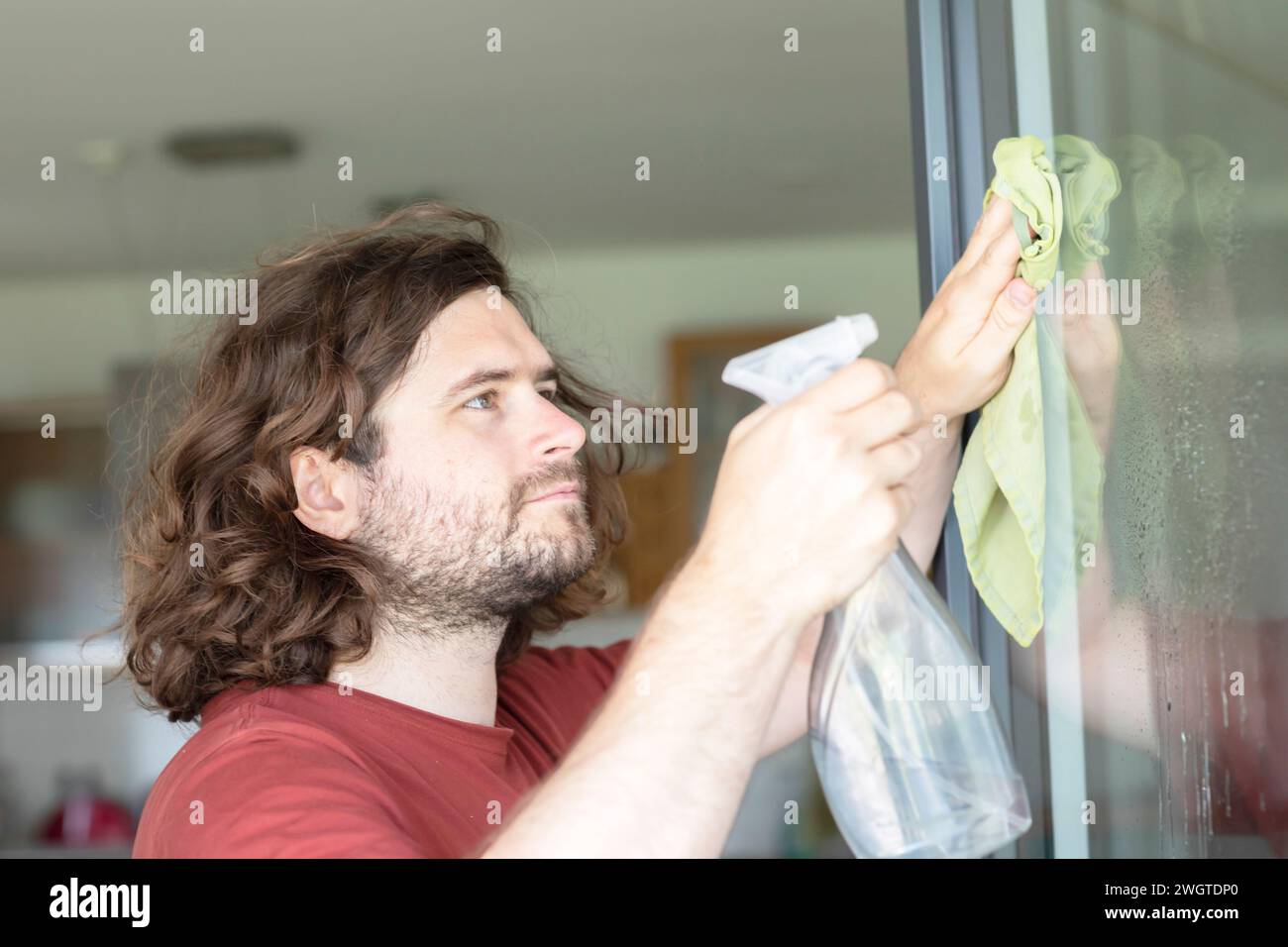 young man cleaning a window at home Stock Photo