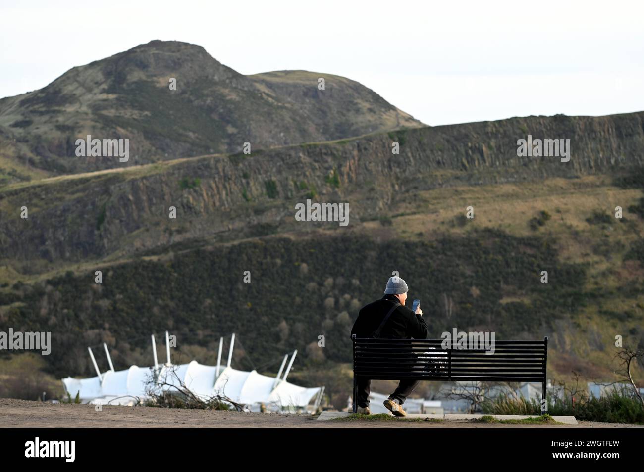 Edinburgh, Scotland, UK. 6th February 2024. Visitors on Calton hill wrapped up against the cold blustery wind and changeable weather conditions with a view towards Arthurs Seat. Credit: Craig Brown/Alamy Live News Stock Photo