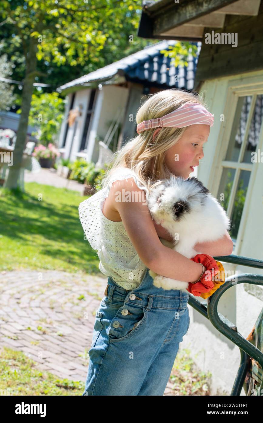 Young girl holding her pet rabbit standing in her garden Stock Photo