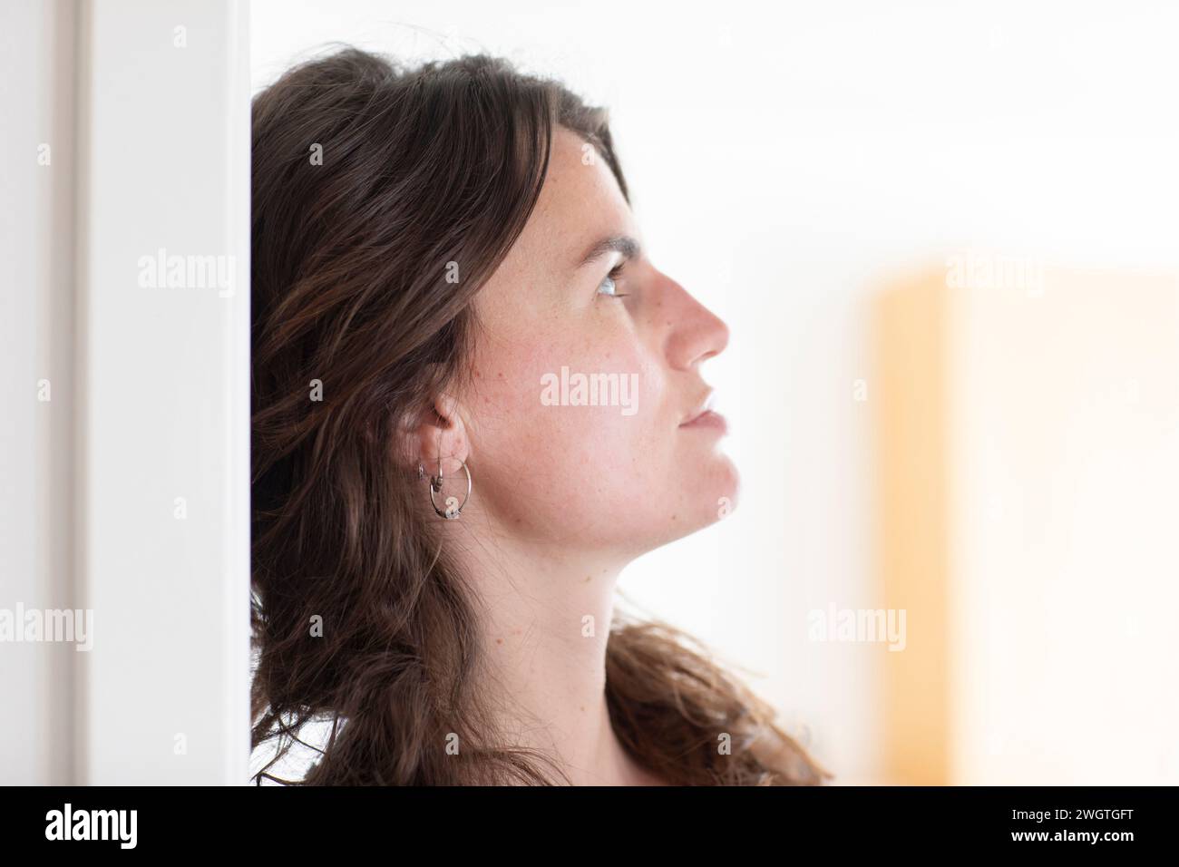 Young woman sitting at home, profile view Stock Photo