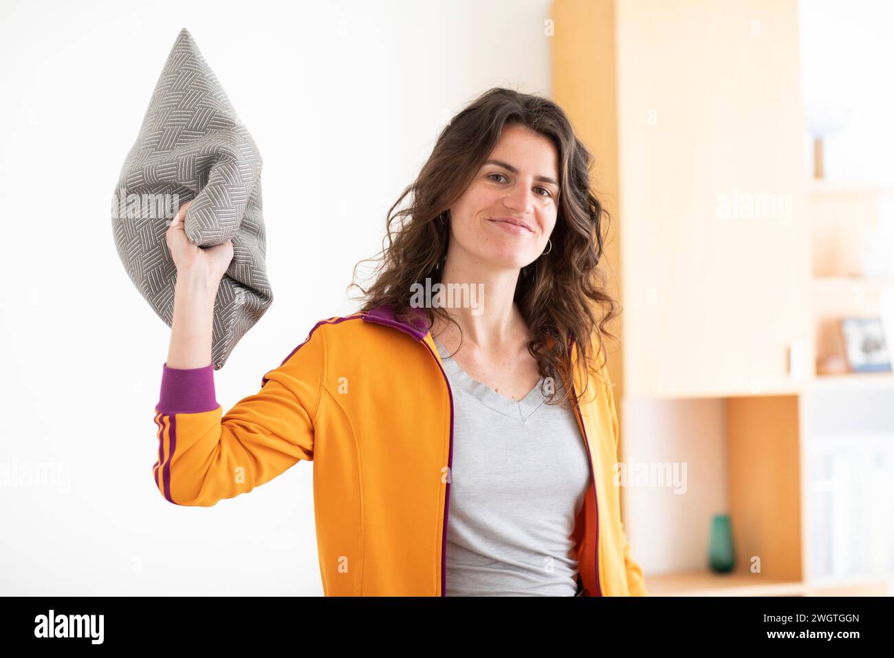 young woman with yellow jacket  throwing pillow Stock Photo