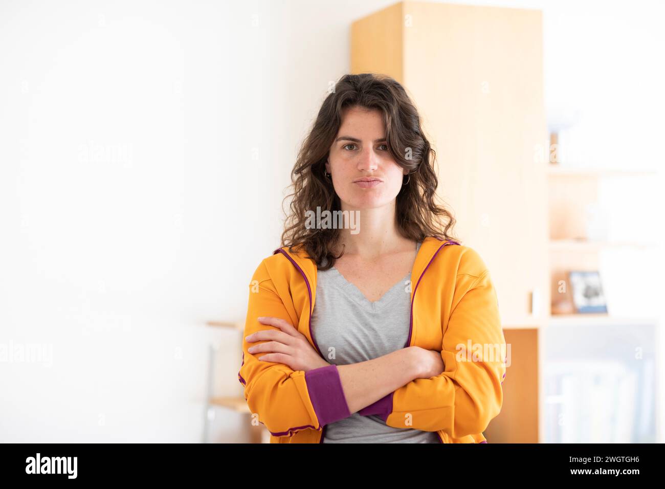 young woman with yellow jacket standing at home Stock Photo