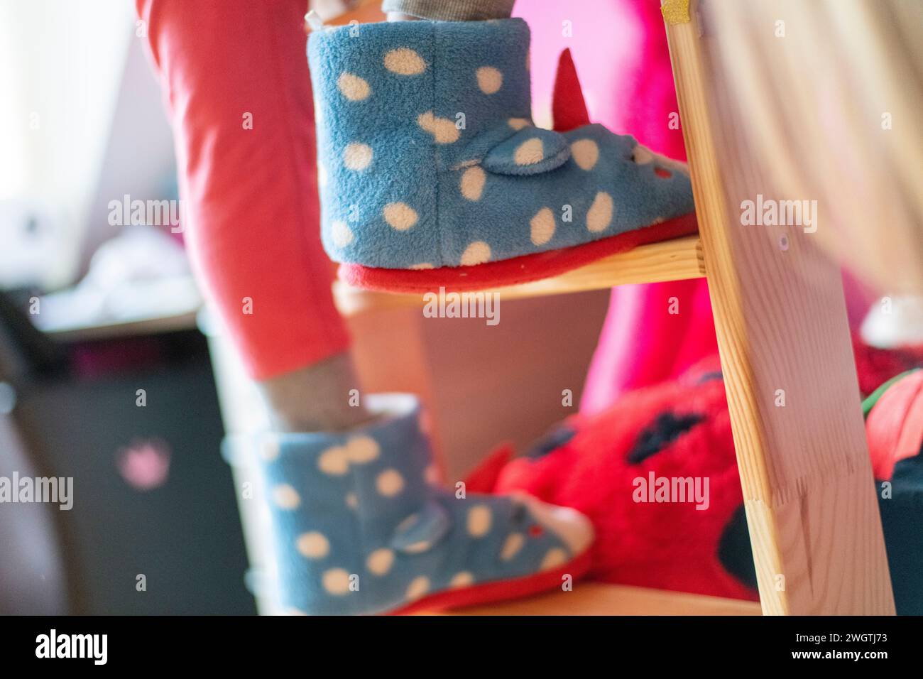 young girl climbing her bunkbed with fluffy slipper shoes on Stock Photo