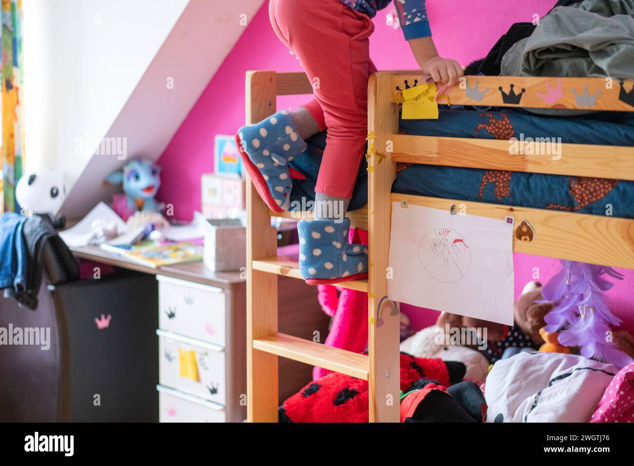young girl climbing her bunkbed with fluffy slipper shoes on Stock Photo