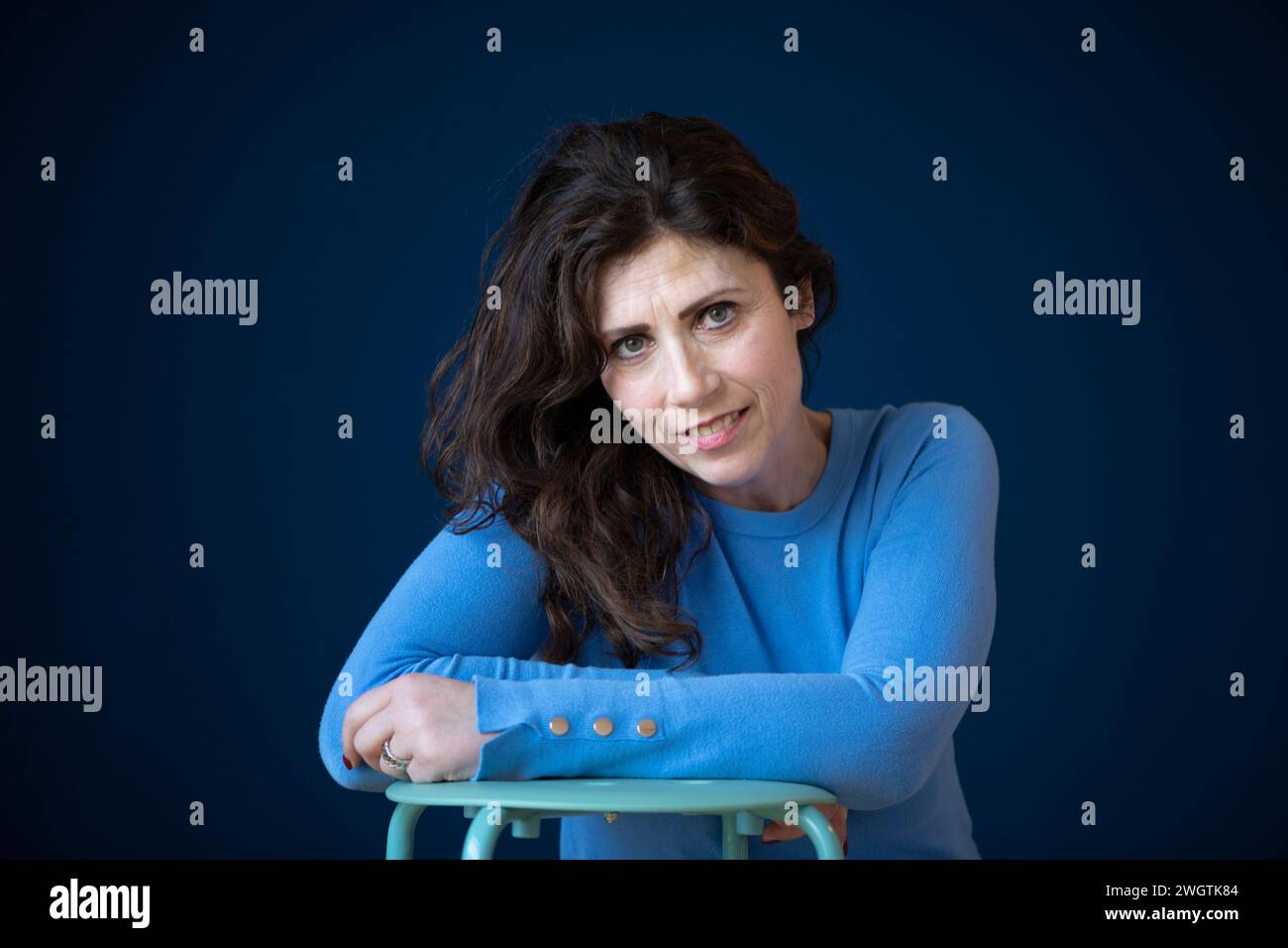 attractive woman, leaning on the back of her chair looking into the camera with a concerned look Stock Photo