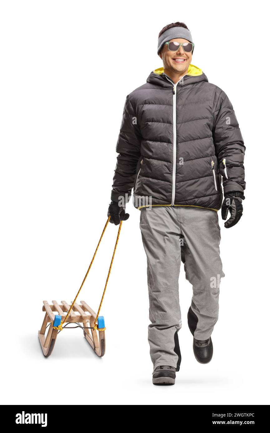 Portrait of a man in a winter jacket walking and pulling a wooden sled isolated on white background Stock Photo