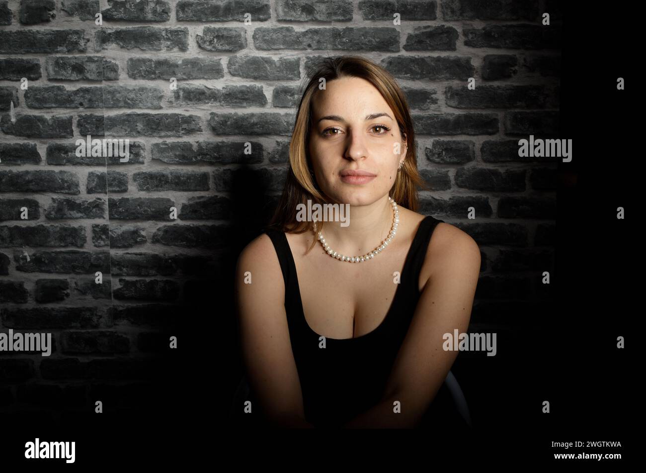 Young woman sitting wall hi-res stock photography and images - Alamy