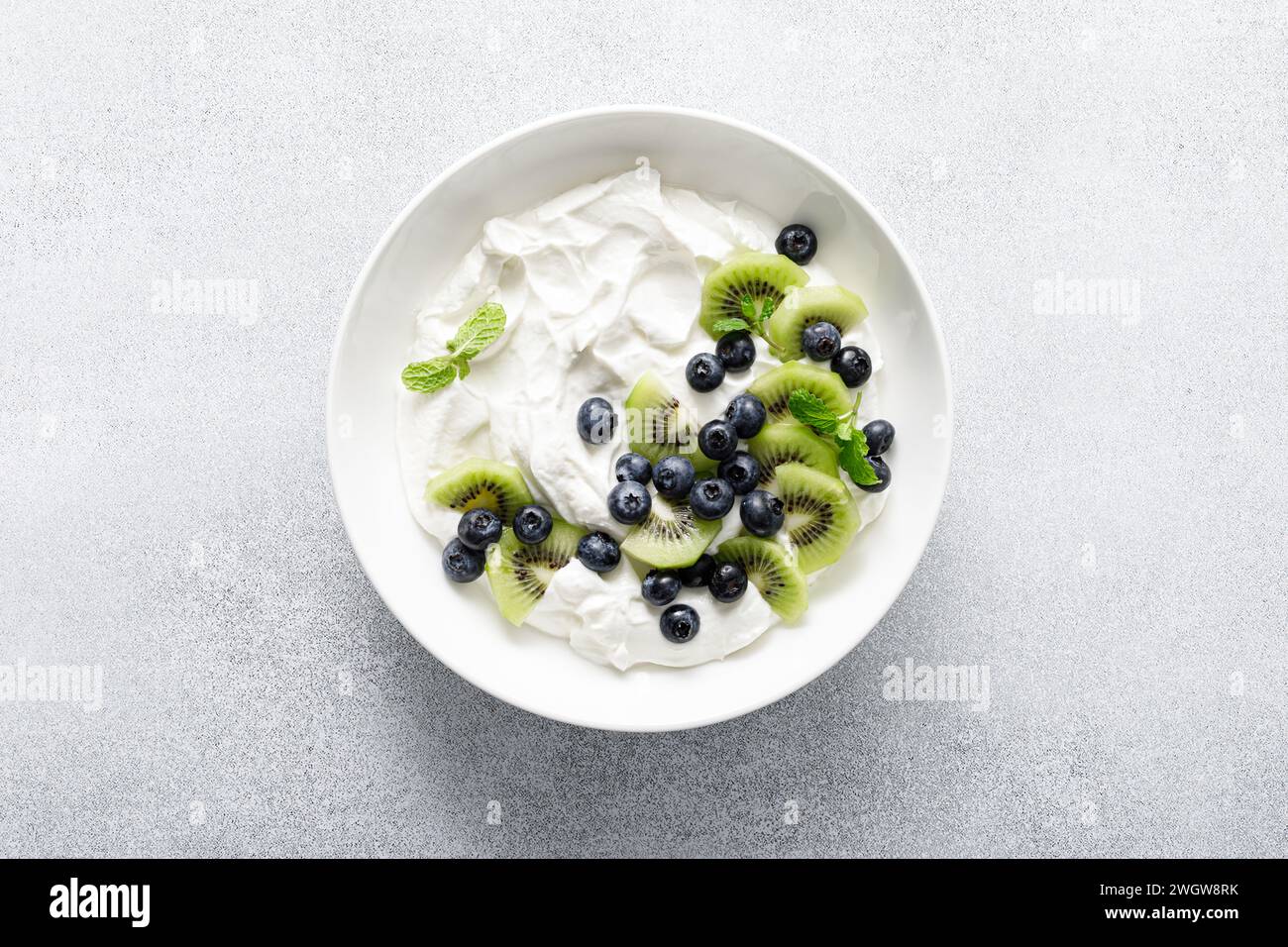 White plain greek yogurt with fresh blueberries and kiwi fruit, top view Stock Photo