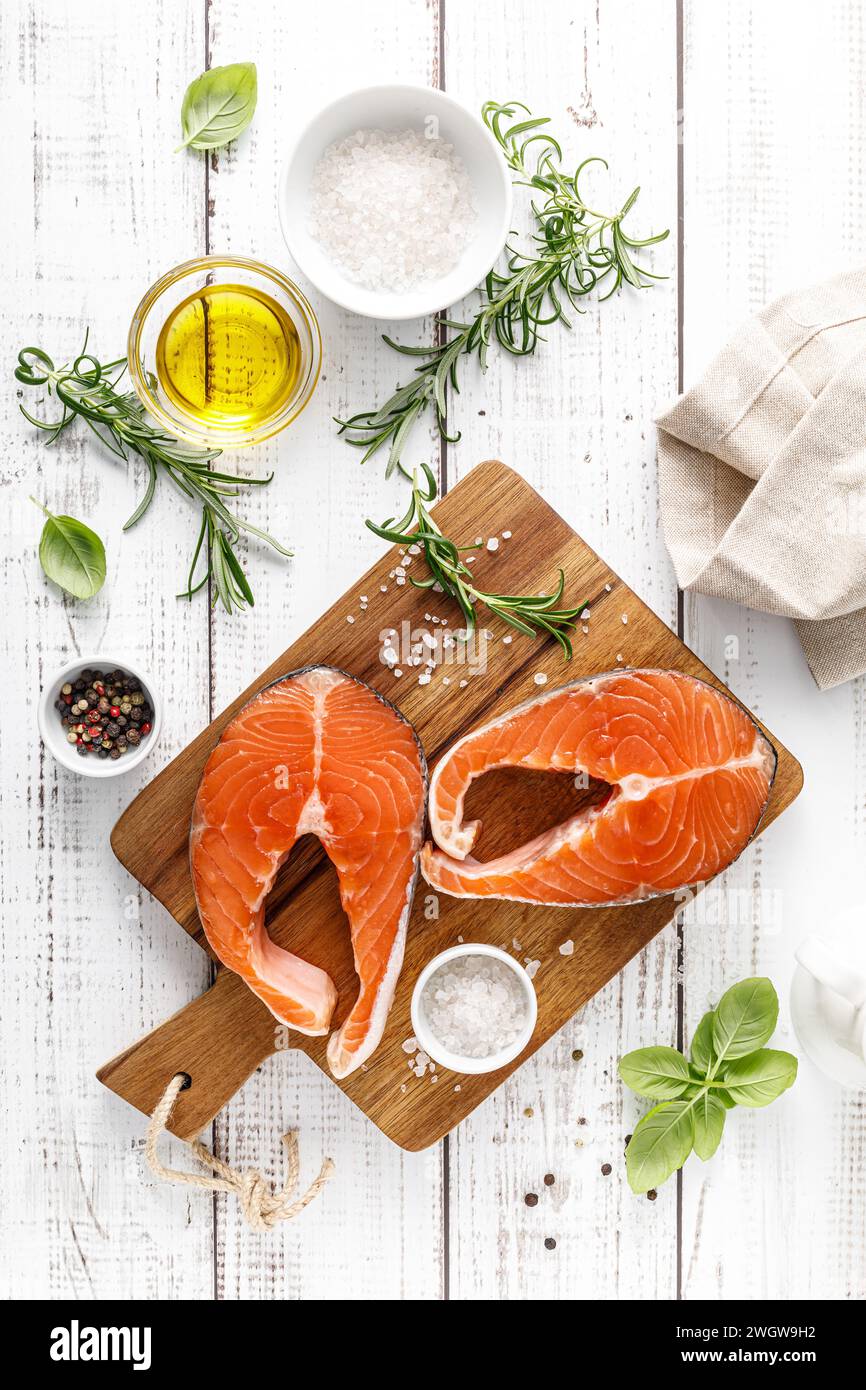 Fresh raw salmon steaks on a board with ingredients for cooking, top view Stock Photo