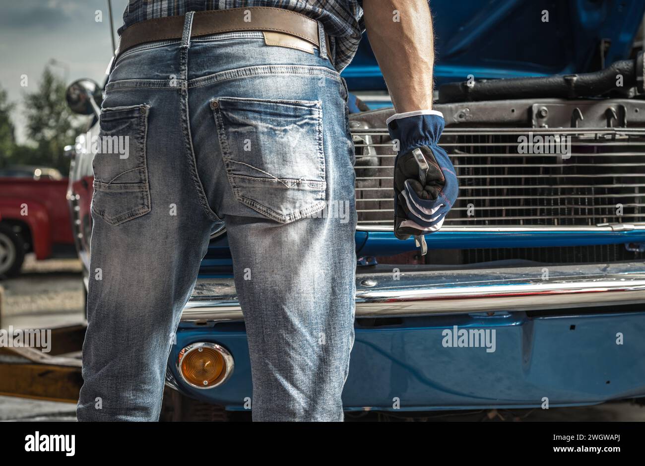 Caucasian Man Working on His Classic Car. Keeping Iron Wrench in His Hands Close Up. Stock Photo