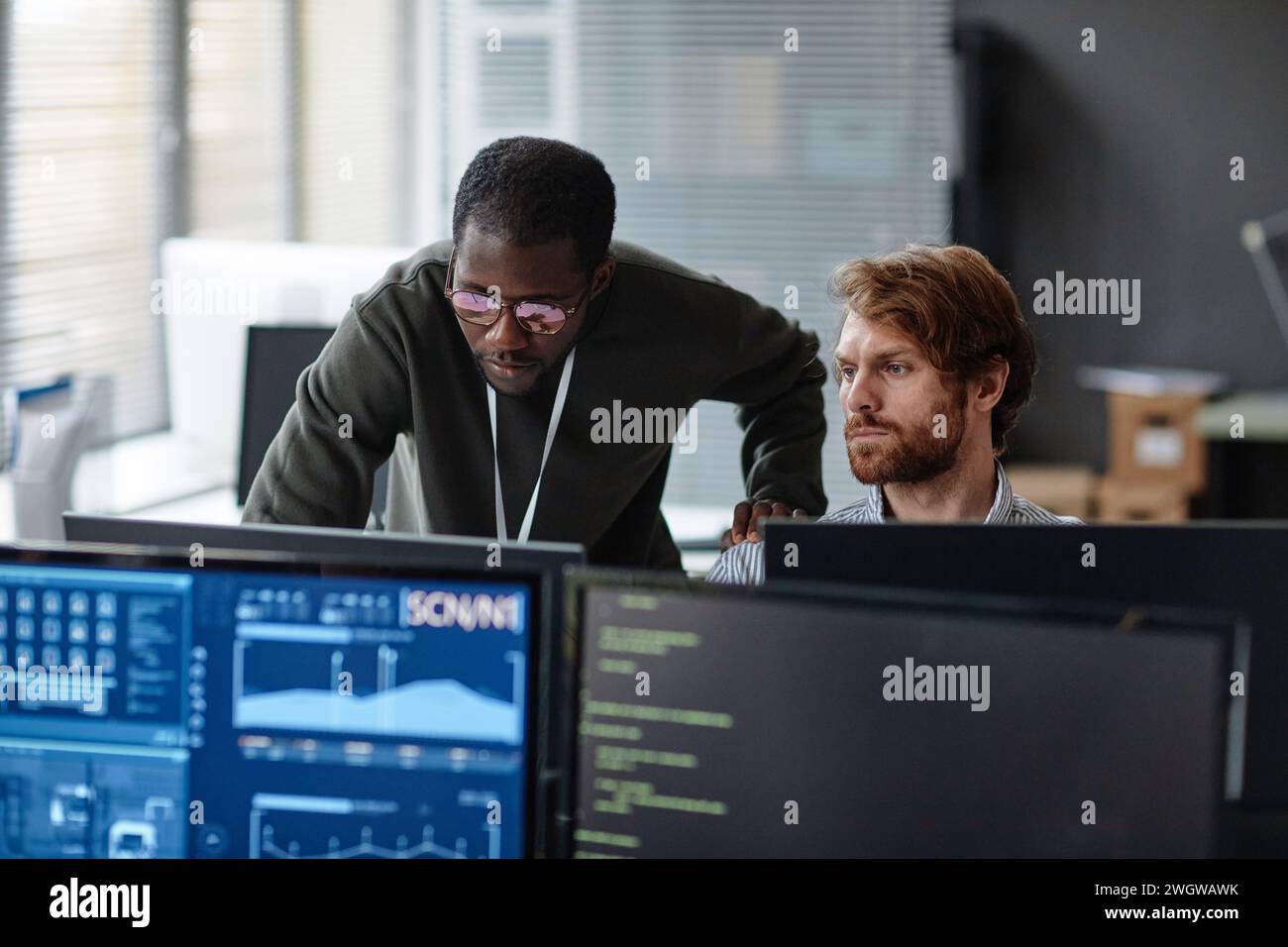 Portrait of two male professionals discussing work issues over computer monitors in cybersecurity office copy space Stock Photo