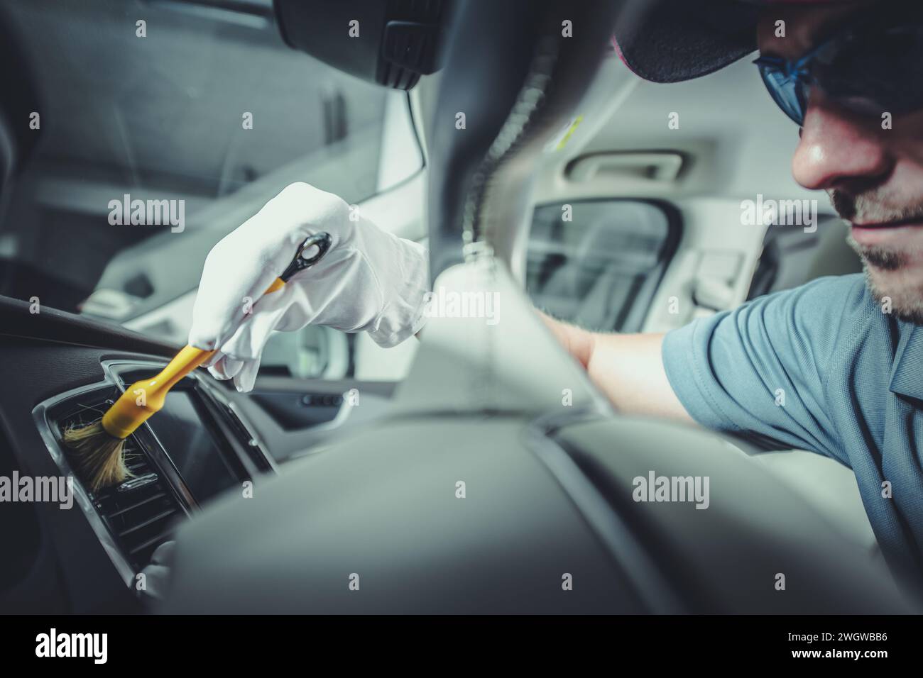 Detailed Car Interior Cleaning Using Professional Brushes. Vehicle Detailing Performed by Caucasian Worker. Stock Photo
