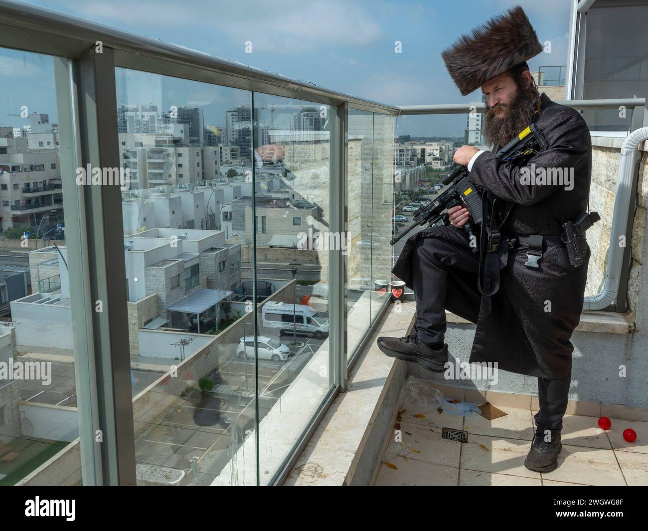 Assaf Peleg, today an Orthodox Jewish rabbi, overlooking the southern Israeli city of Kiryat Malachi on February 6, 2024. Peleg comes from a kibbutz member and became an officer in the IDF, a Captain who served in a an elite unit, fighting throughout the second intifada. Today, Peleg, in his early 40s, is a religious Hasid and the father of seven who shares his vast military knowledge with various civil security tasks he undertakes, such as the emergency response team he helped to establish and train in the city of Kiryat Malachi. Since the October 7 Hamas atrocities and war, he has been armed Stock Photo